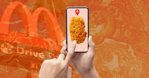 Hands holding a smartphone displaying a chicken nugget with a location tag.